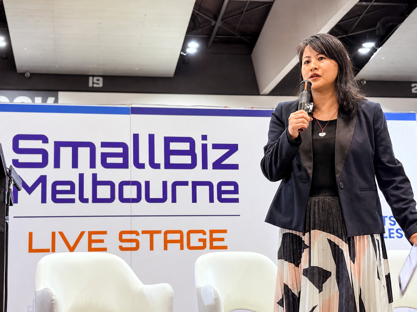 Lucy Lin speaking with a microphone on the SmallBiz Melbourne live stage